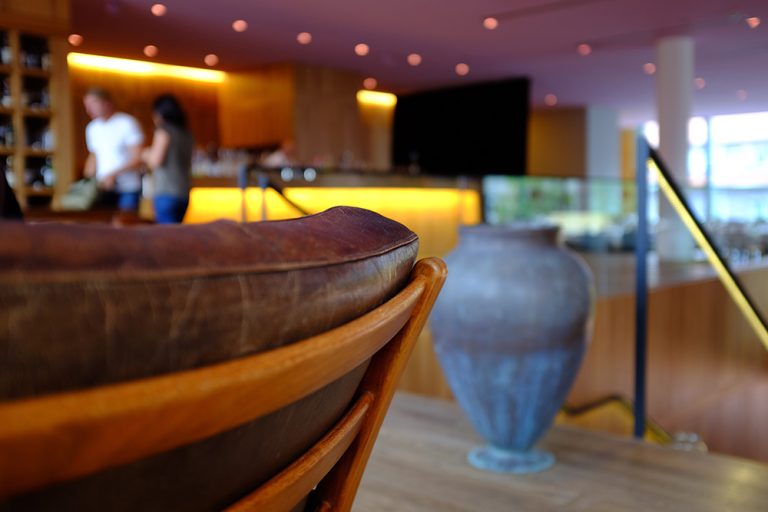 Ledersessel und Vase vor der beleuchteten Bar im il Boccone Konstanz