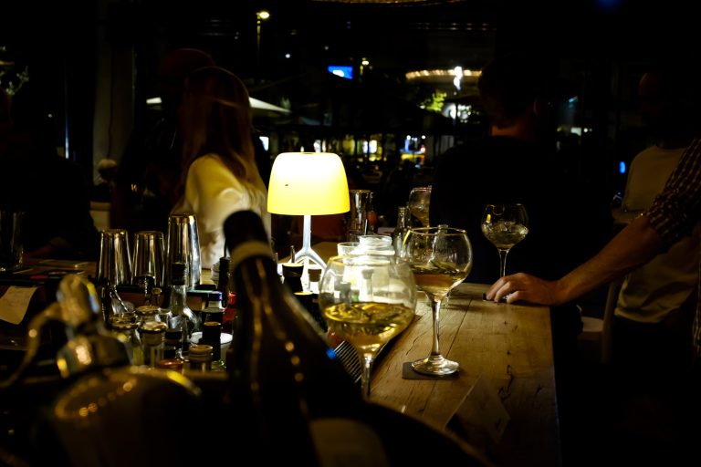 Gäste mit Weingläsern an der Bar am Abend – il Bar in Konstanz
