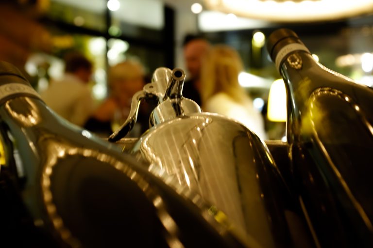 Champagnerflaschen im Kühler, dahinter Gäste im il Boccone Konstanz